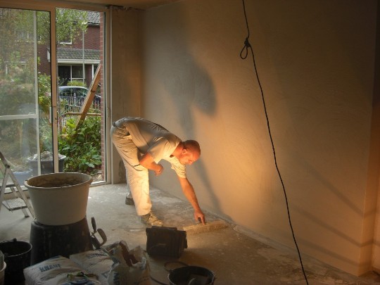 Vakman bezig met stucwerk bij een raam